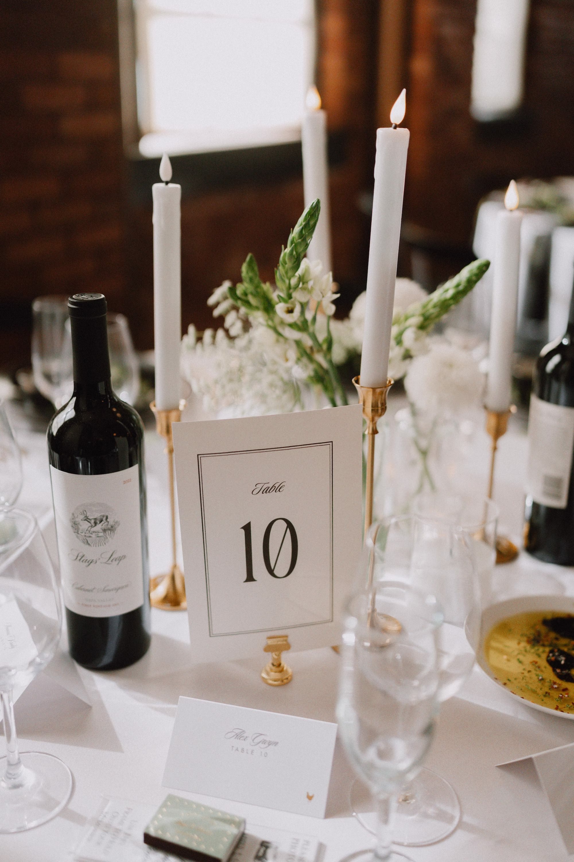 27Classic Modern Black and White Wedding Ideas - Modern Black and Ivory Ybor City Wedding | J.C. Newman Cigar Co. White Taper Candles in Gold Holders, Wine Bottle and Black and White Table Number Modern Wedding Reception Centerpiece Ideas