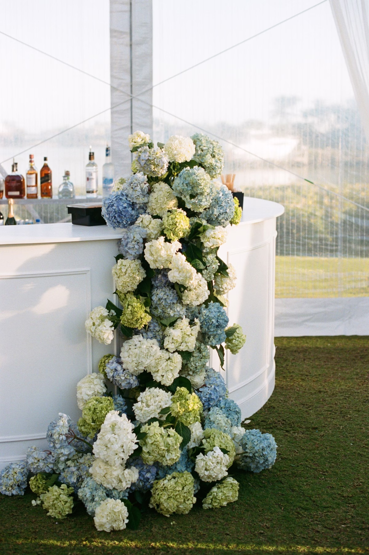 27Coastal Nancy Meyers Inspired Florida Beach Wedding - Coastal Blue, White, and Green Sarasota Wedding | The Resort at Longboat Key Club White Wedding Bar with Cascading Blue and White Hydrangea Floral Installation Cocktail Hour Bar Decor Ideas