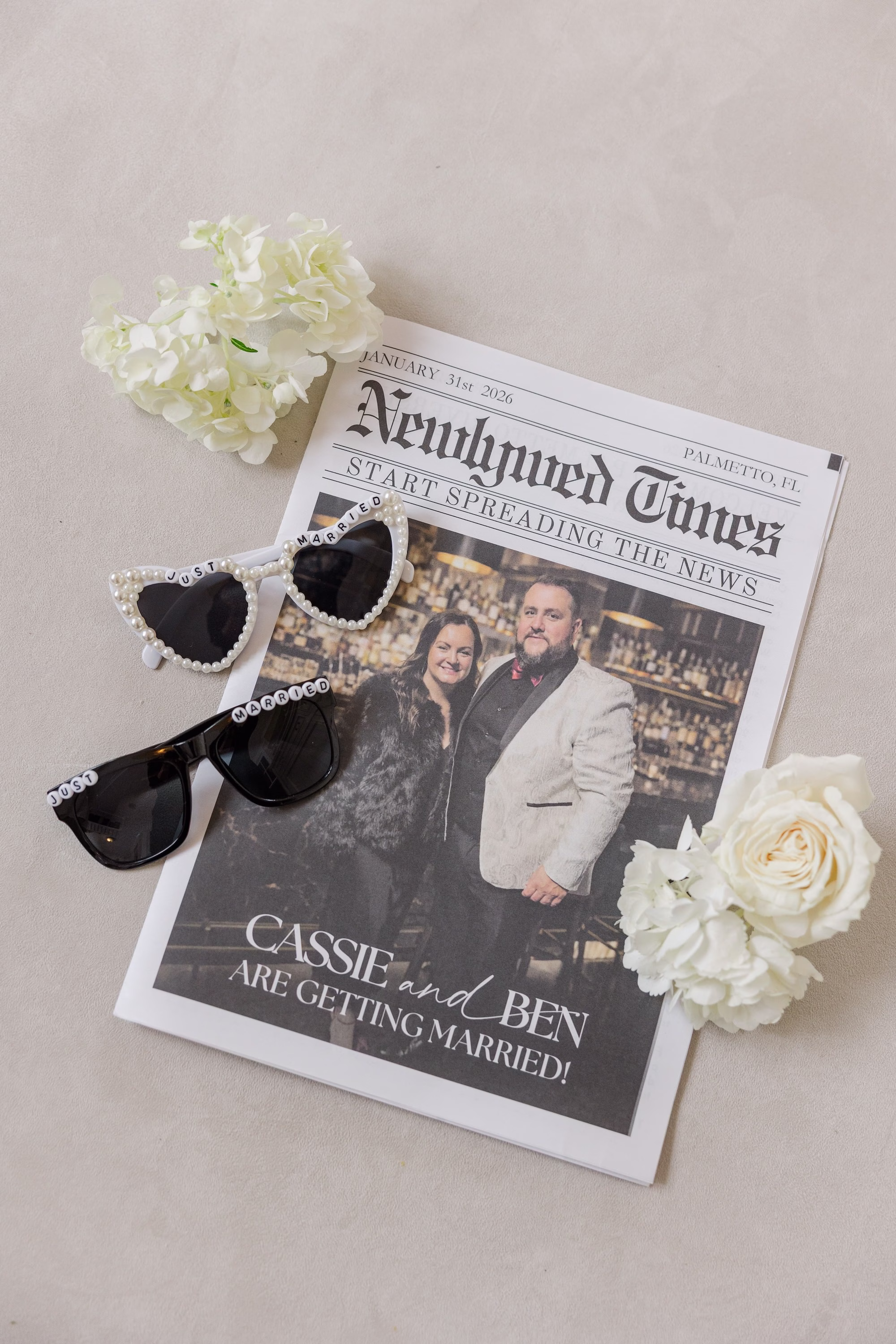 Custom Newlywed Times Newspaper Wedding Program with Pearl Heart Sunglasses and Black Invitation Flat Lay Ideas