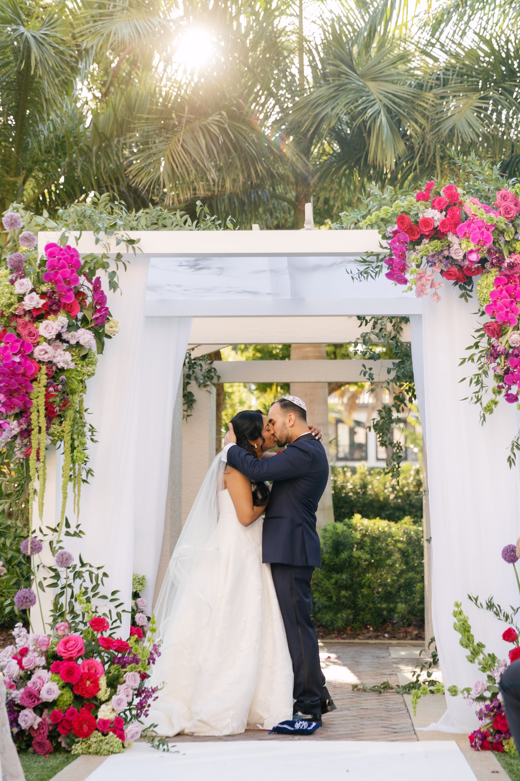 Bride and Groom First Kiss Wedding Portrait Under Floral Chuppah | St. Pete Florist Bruce Wayne Florals