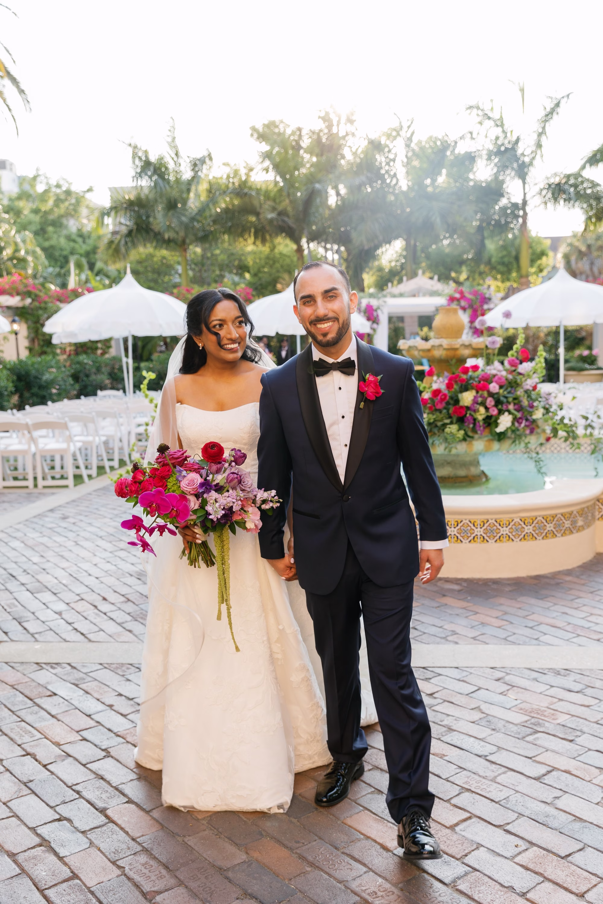 Bride and Groom Just Married Wedding Portrait Walking Through Garden Courtyard with Vibrant Pink and Purple Bouquet | St. Pete Florist Bruce Wayne Florals