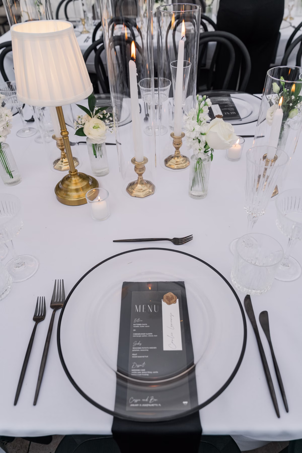 Black Rimmed Glass Charger with Black Menu Card, Black Flatware, Gold Candlestick Lamp and Taper Candles Wedding Place Setting Ideas | Palmetto Rentals Kate Ryan Event Rentals