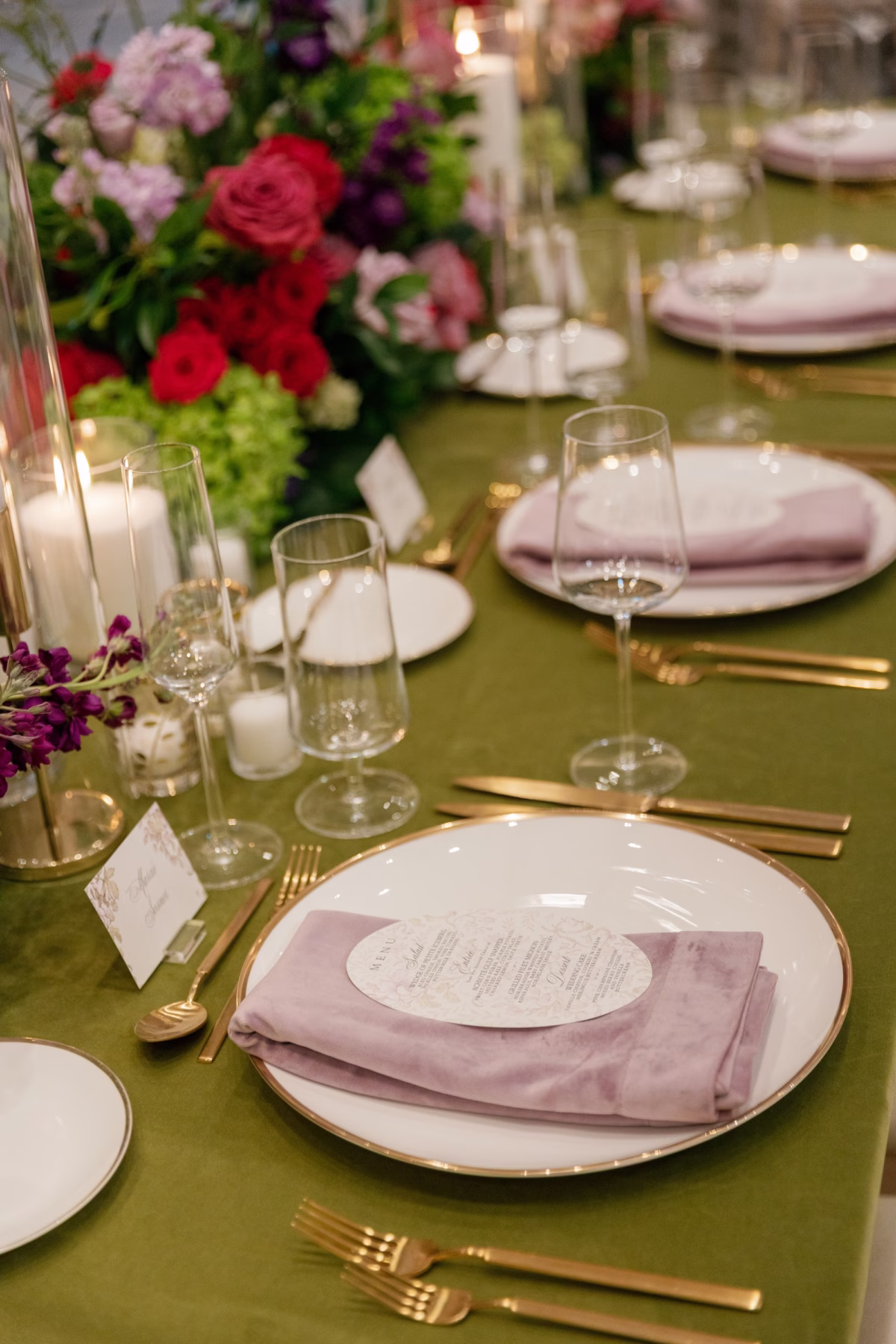 Gold Rimmed Charger with Blush Velvet Napkin, Gold Flatware and Vibrant Red and Pink Rose Centerpiece on Green Velvet Linen Wedding Tablescape Ideas | St. Pete Florist Bruce Wayne Florals
