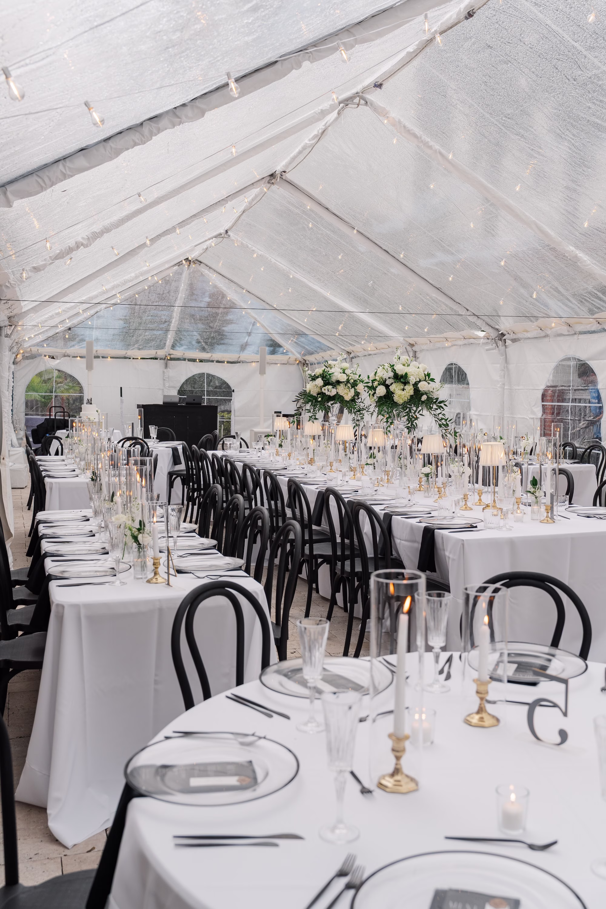 Clear Tent Wedding Reception with Round and Long White Tables, Black Bentwood Chairs and String Lights Ideas | Wedding Reception at Palmetto Venue Palmetto Riverside Bed and Breakfast | Rentals Fiesta Solutions Event Rentals | Rentals Kate Ryan Event Rentals
