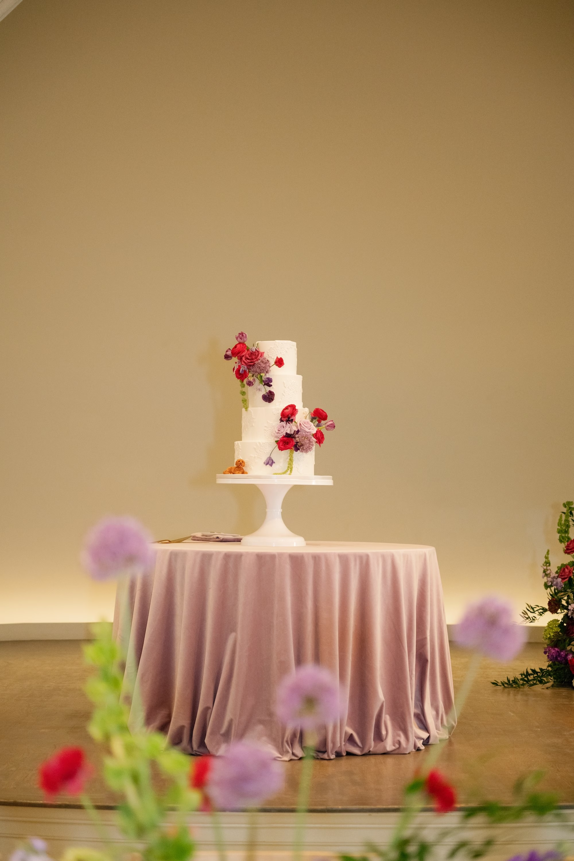 Elegant Round Three-Tier White Wedding Cake with Cascading Fuchsia, Purple and Red Flowers on Blush Velvet Linen Ideas | St. Pete Florist Bruce Wayne Florals