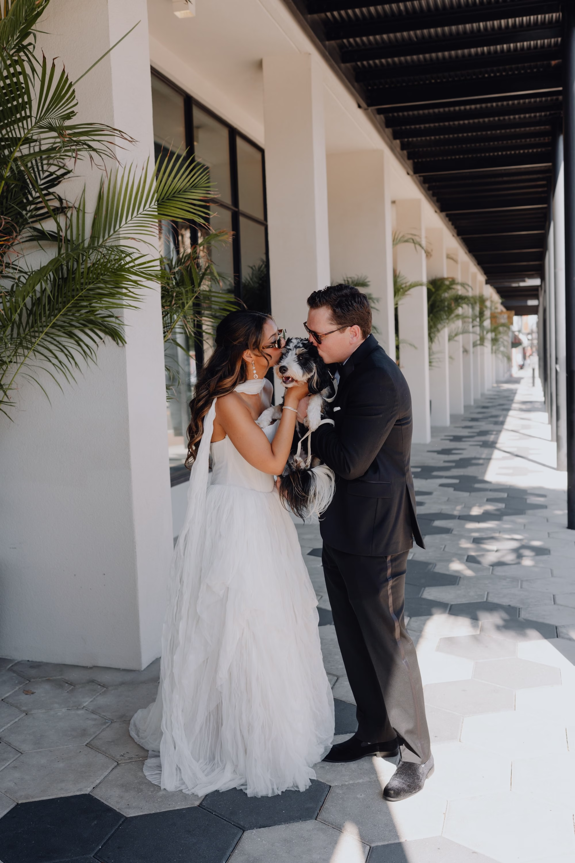 5Classic Modern Black and White Wedding Ideas - Modern Black and Ivory Ybor City Wedding | J.C. Newman Cigar Co. Bride and Groom Kissing Their Dog Wedding Portrait in Black Tuxedo and Ivory Wedding Dress Under Modern Covered Walkway