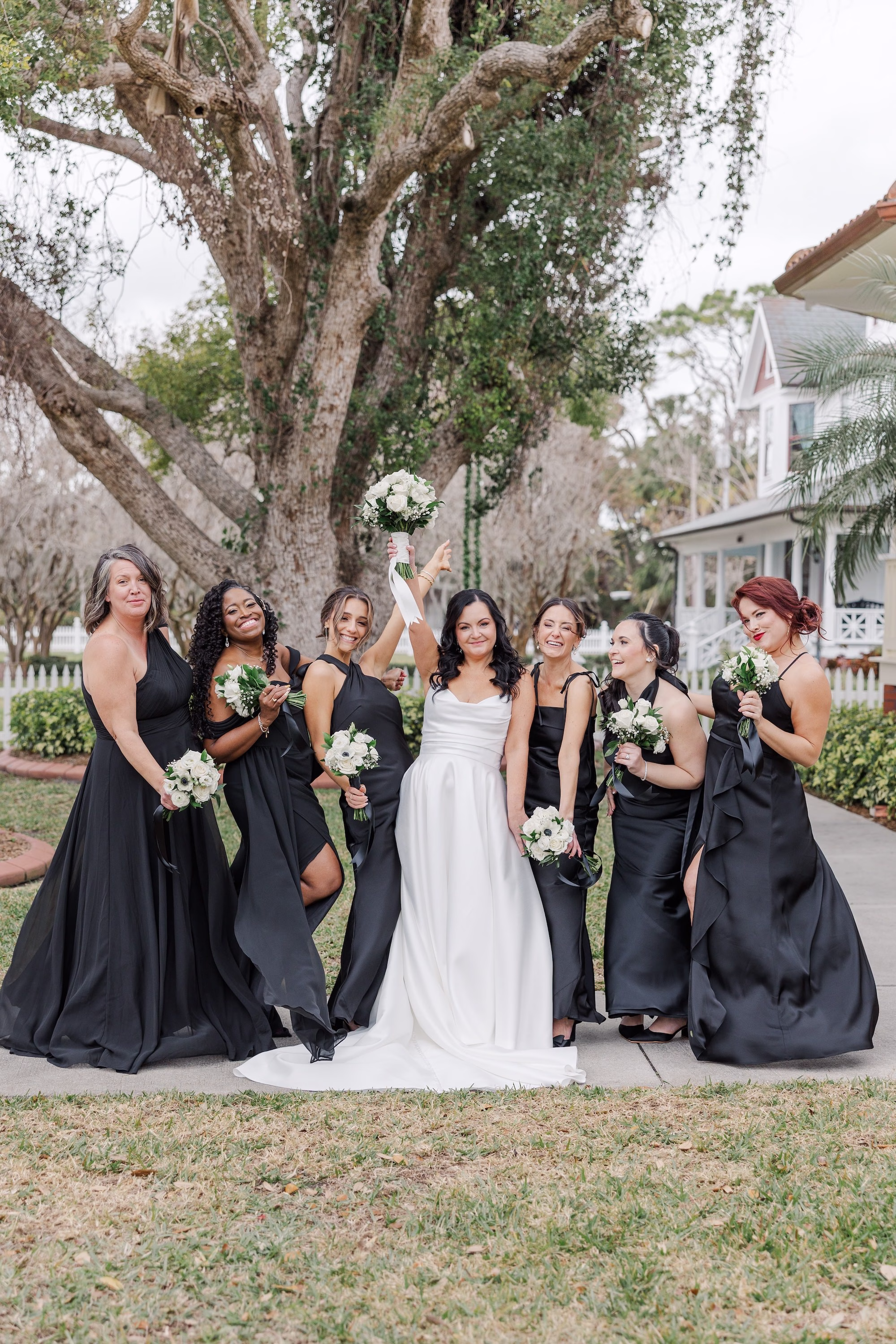 Bride and Bridesmaids Wedding Party Portrait in Mismatched Black Bridesmaid Dresses with White Bouquets Under Live Oak Tree