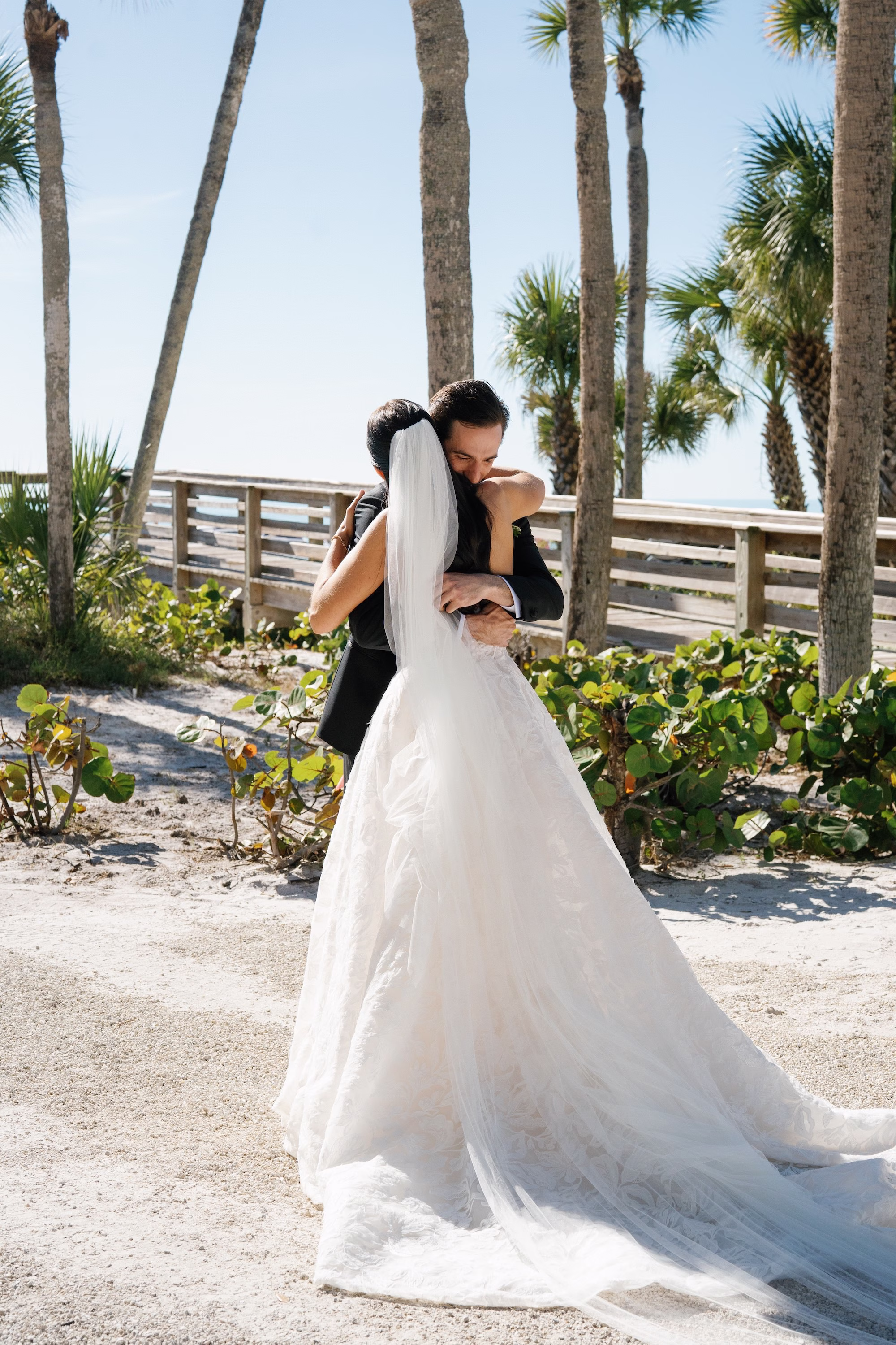 9Coastal Nancy Meyers Inspired Florida Beach Wedding - Coastal Blue, White, and Green Sarasota Wedding | The Resort at Longboat Key Club Bride and Groom First Look Embrace Wedding Portrait Under Palm Trees on Longboat Key