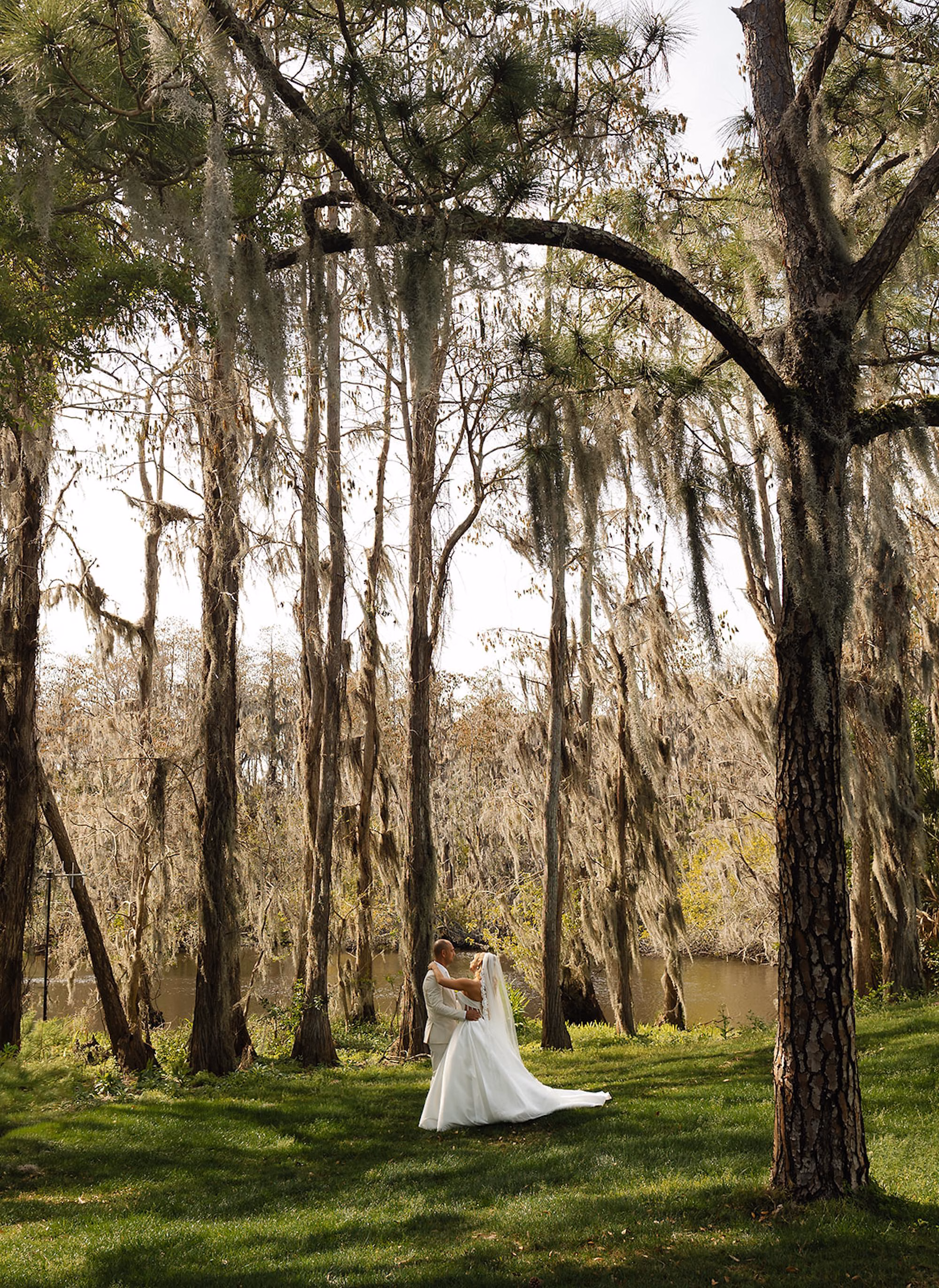 Bride and Groom Embracing Among Tall Cypress Trees and Spanish Moss Beside Lake | Palm Harbor Event Venue Innisbrook Resort