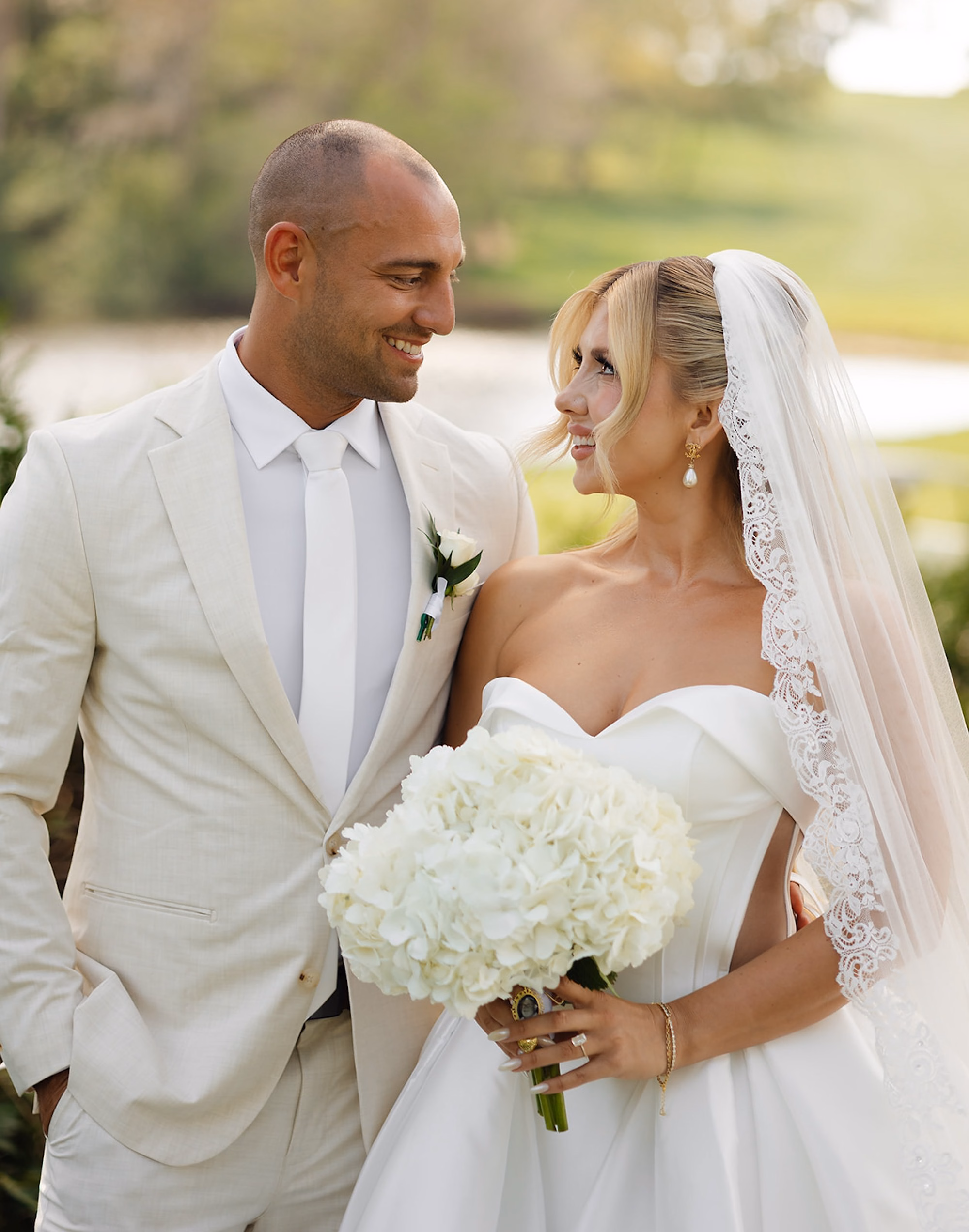 Bride and Groom Portrait with White Hydrangea Bouquet, Lace-Trimmed Veil and Cream Linen Suit