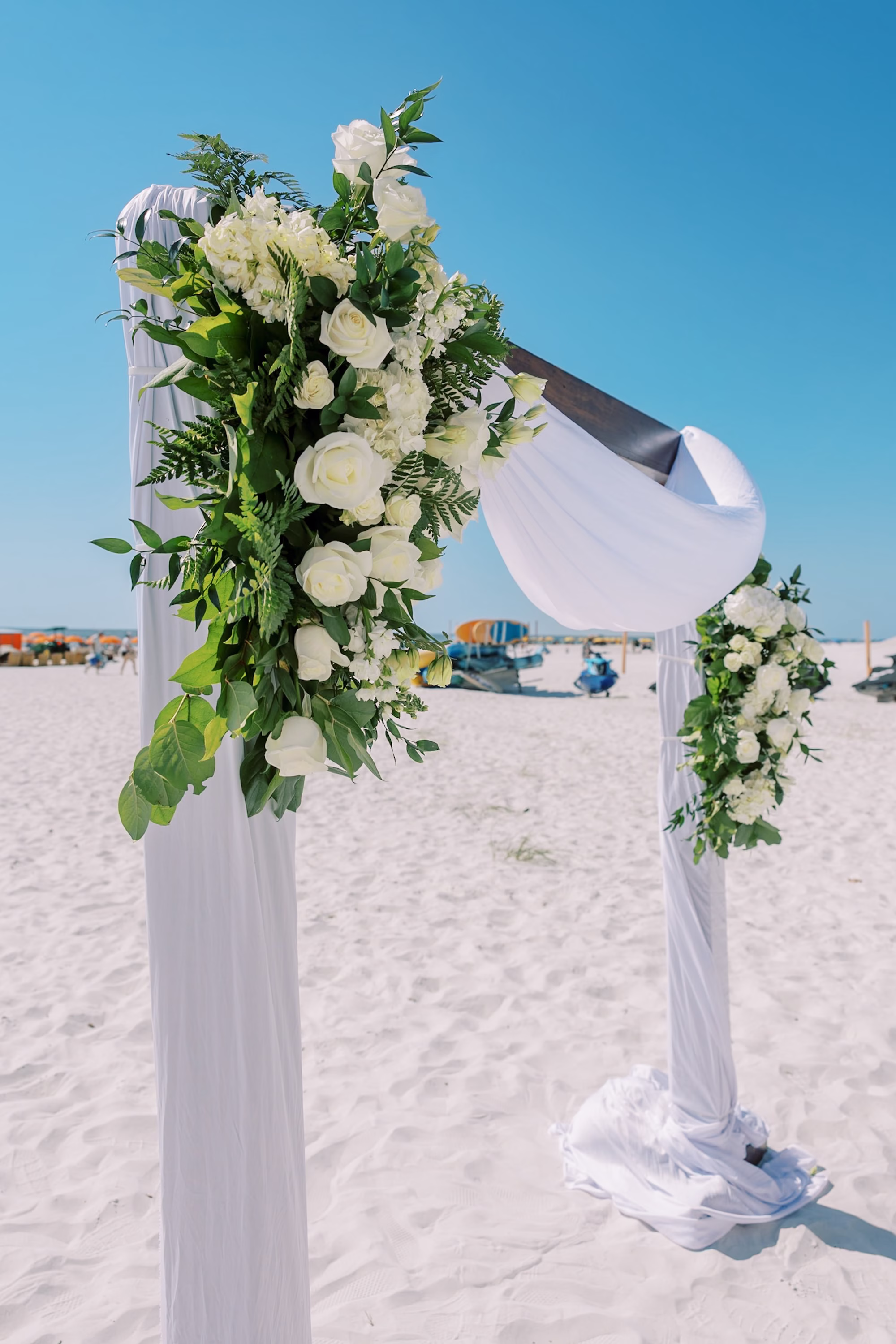 White Draped Beach Wedding Arch with White Rose and Greenery Arrangement Ideas | Clearwater Beach Rentals Gabro Event Services