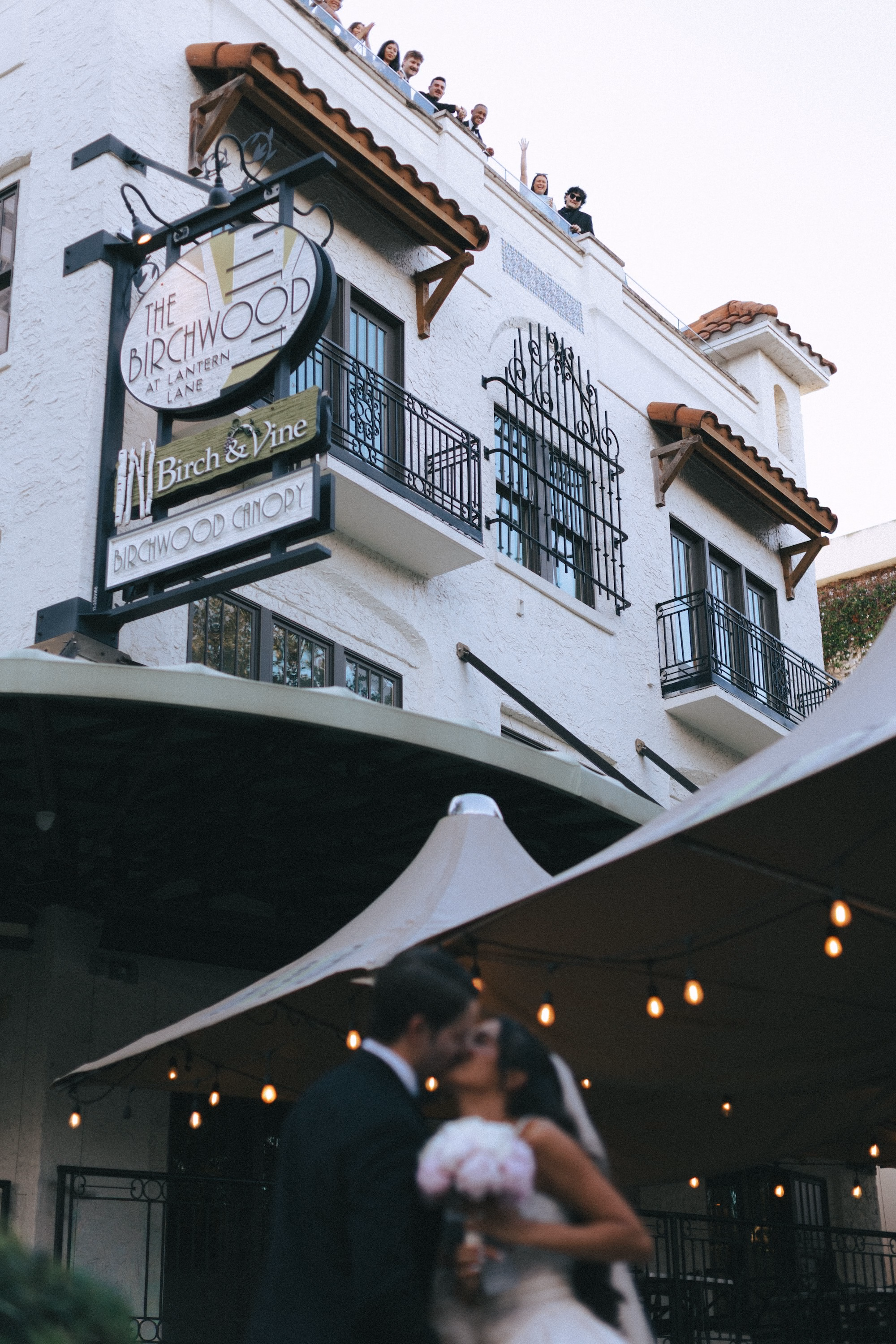 Bride and Groom Kissing Under String Lights Beneath Historic Hotel Wedding Venue Sign | St. Pete Venue The Birchwood