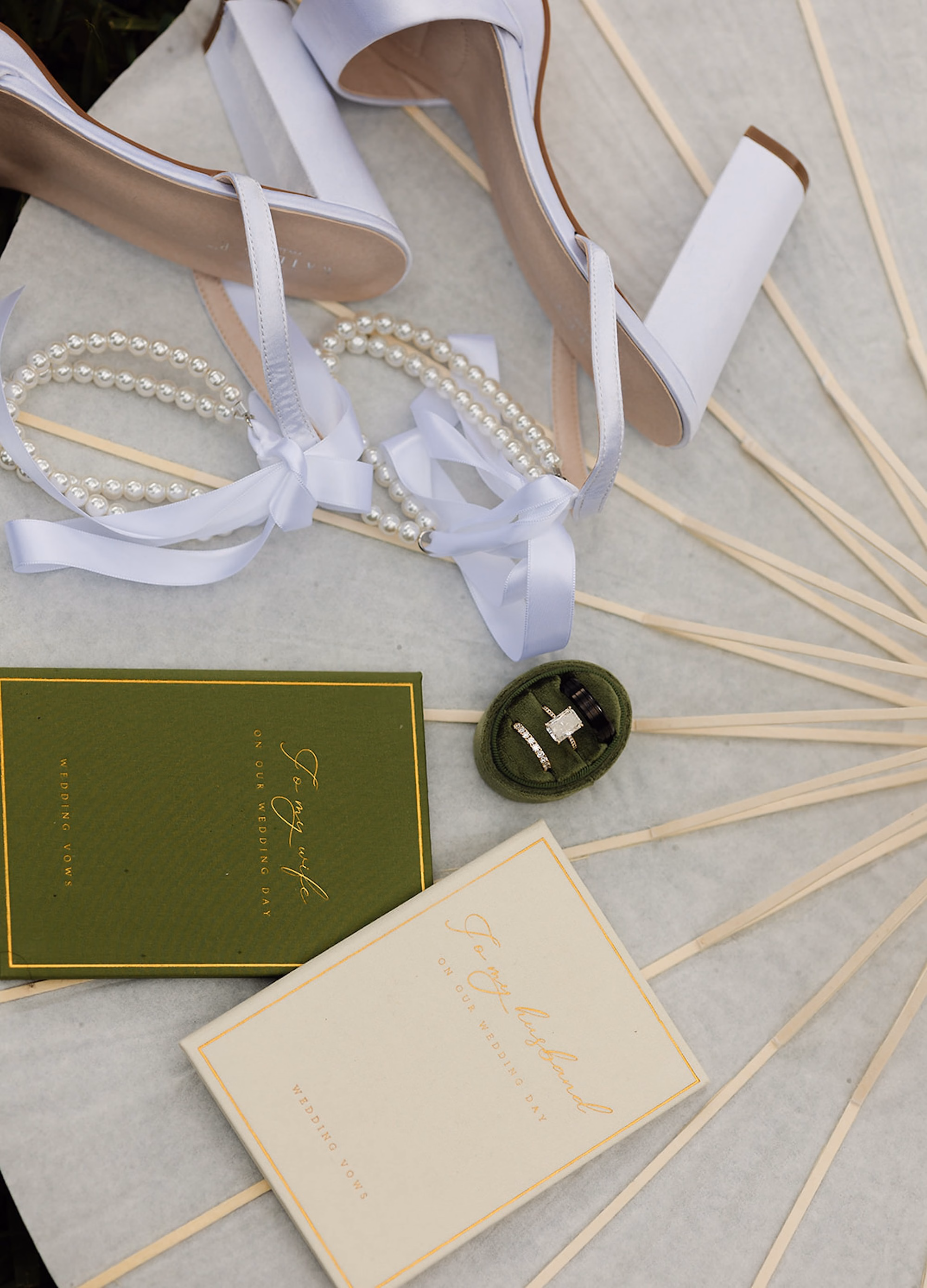 Bridal Details Flat Lay with White Satin Heels, Pearl Bracelet, Olive Green Vow Books and Jade Ring Box Ideas