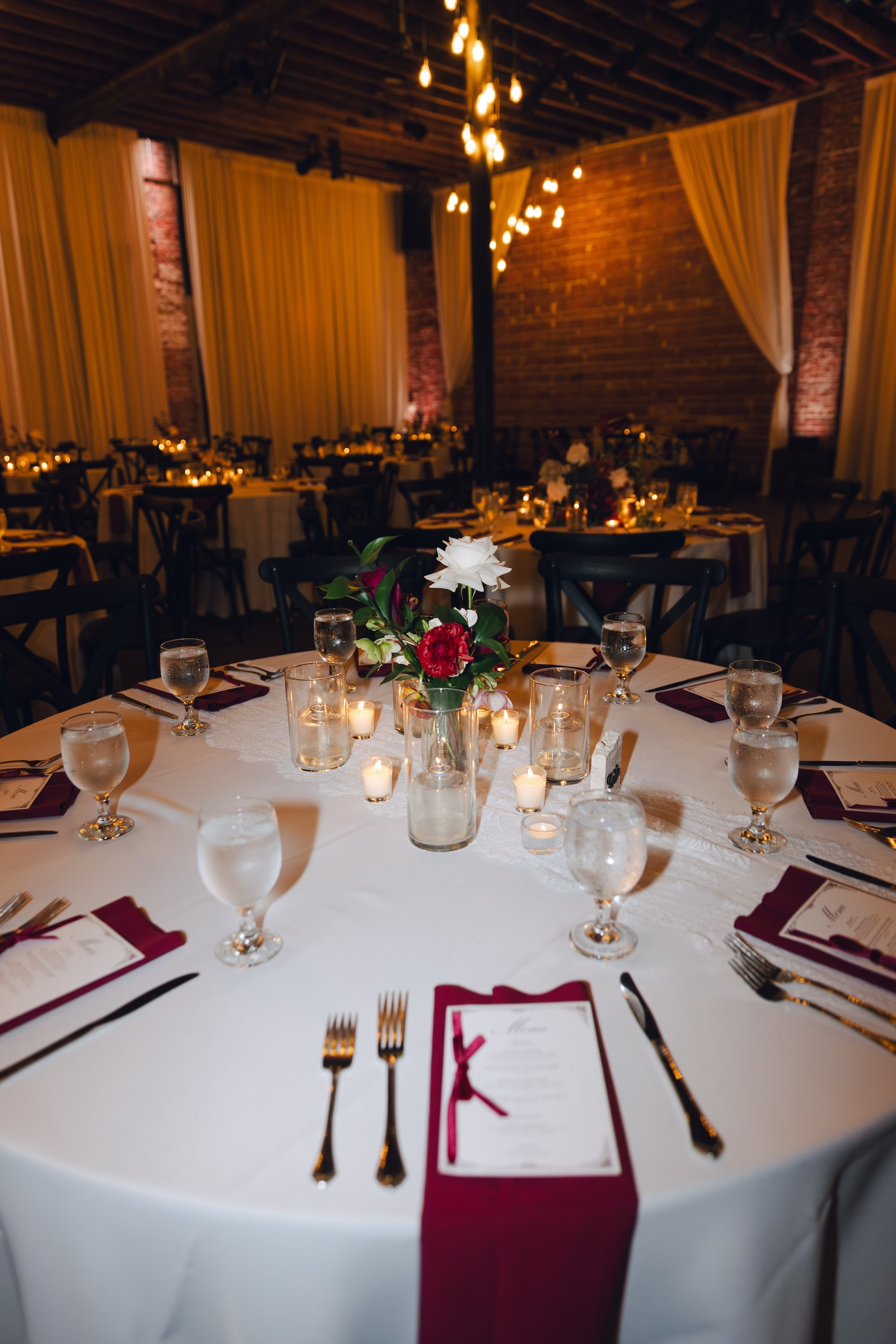 22Burgundy Vintage Romance Wedding Ideas - Vintage Romance Pink and Burgundy Downtown St. Pete Wedding | NOVA 535 Wedding Reception Table with White Linens, Burgundy Napkins, Gold Flatware and Red Rose Bud Vase in Exposed Brick Ballroom with White Draping Decor Ideas | St. Pete Venue NOVA 535