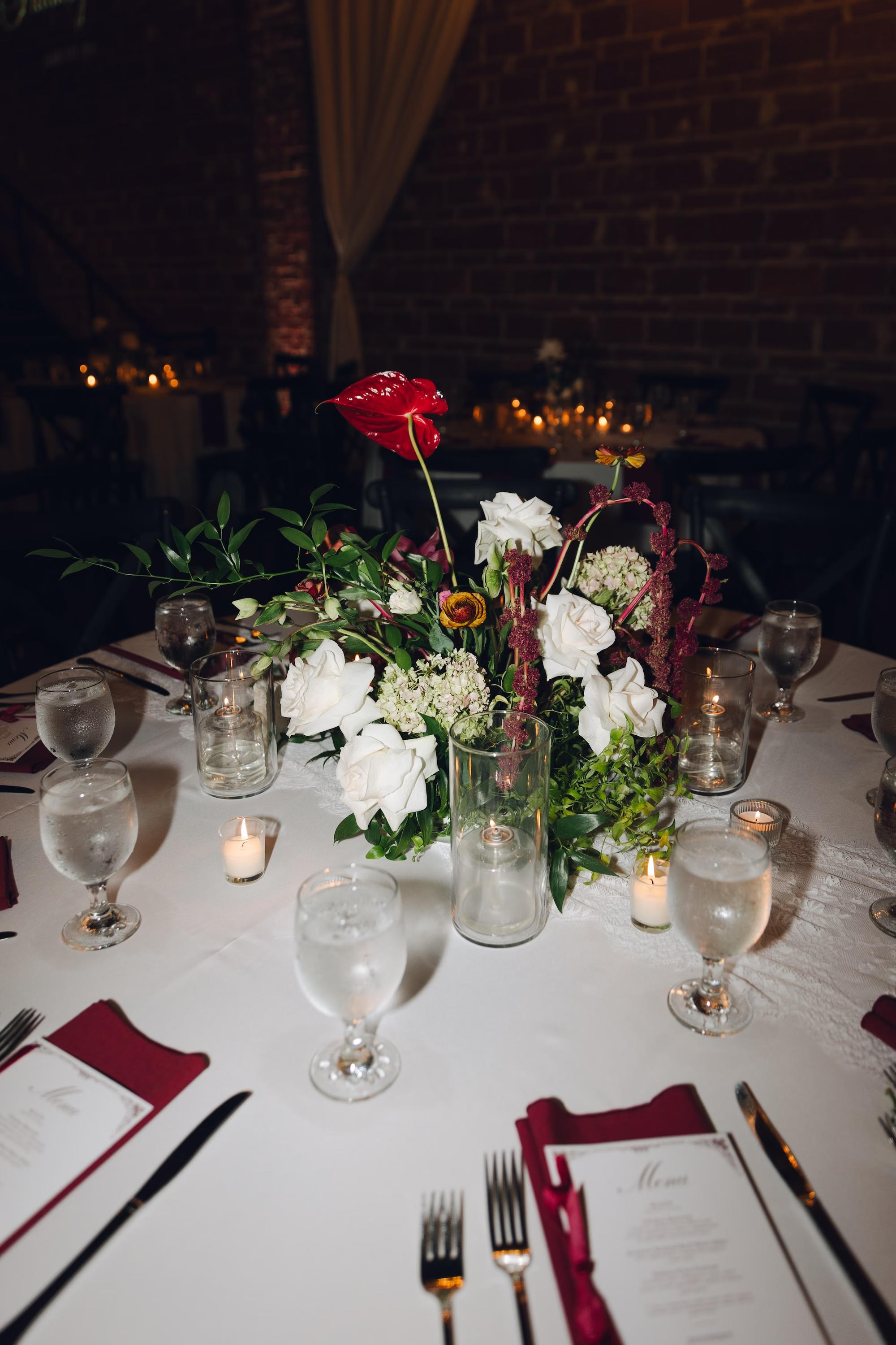 27Burgundy Vintage Romance Wedding Ideas - Vintage Romance Pink and Burgundy Downtown St. Pete Wedding | NOVA 535 Wedding Reception Table with Burgundy Anthurium and White Rose Centerpiece, Burgundy Napkins and Candles in Exposed Brick Ballroom Decor Ideas