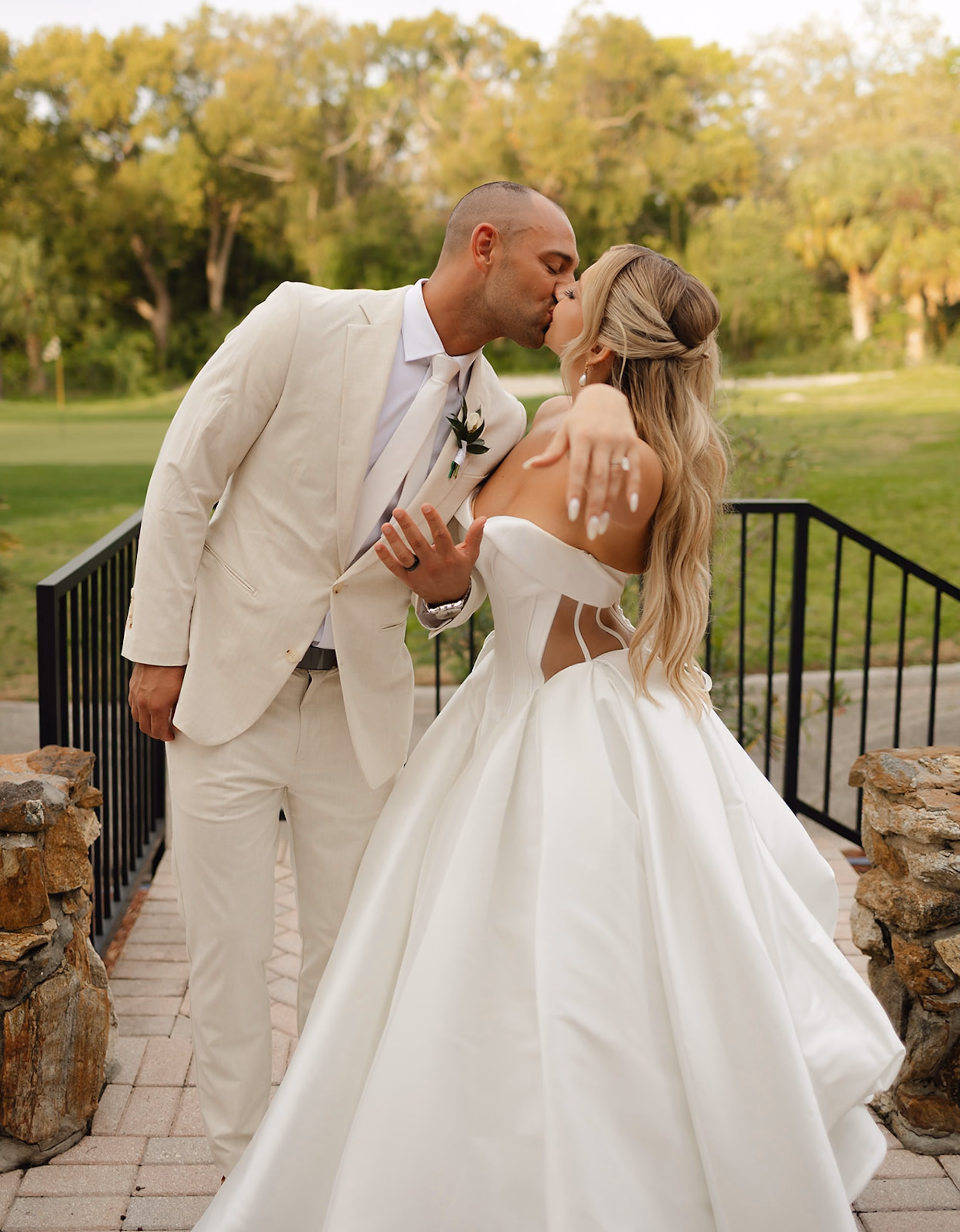 Groom Kissing Bride on Stone Bridge with Golf Course Behind | Palm Harbor Venue Innisbrook Golf & Spa Resort