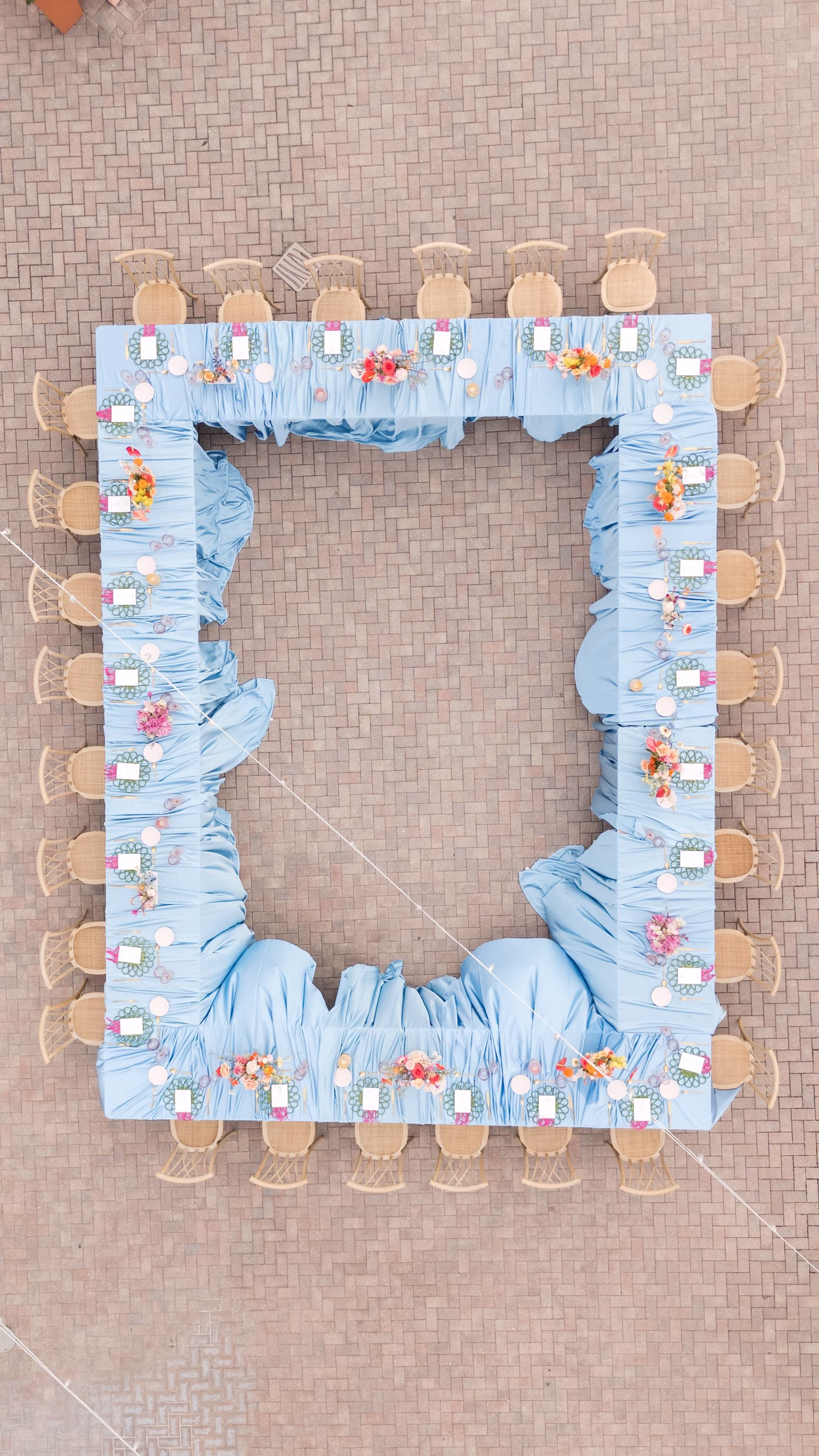 Aerial View of Rectangular Sky Blue Linen Wedding Reception Table with Crossback Chairs and Colorful Centerpieces on Rooftop Terrace | Venue Hyatt Regency Clearwater Beach | Planner Wilder Mind Events | Rentals Kate Ryan Event Rentals | Fancy That Specialty Linens