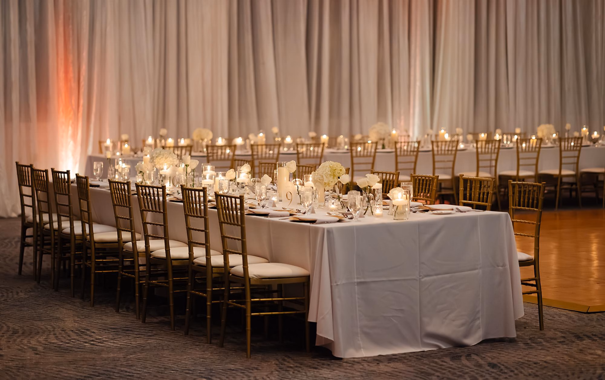 Ballroom Wedding Reception with Long White Linen Tables and Gold Chiavari Chairs Against White Draped Wall Decor Ideas | Palm Harbor Venue Innisbrook Golf & Spa Resort