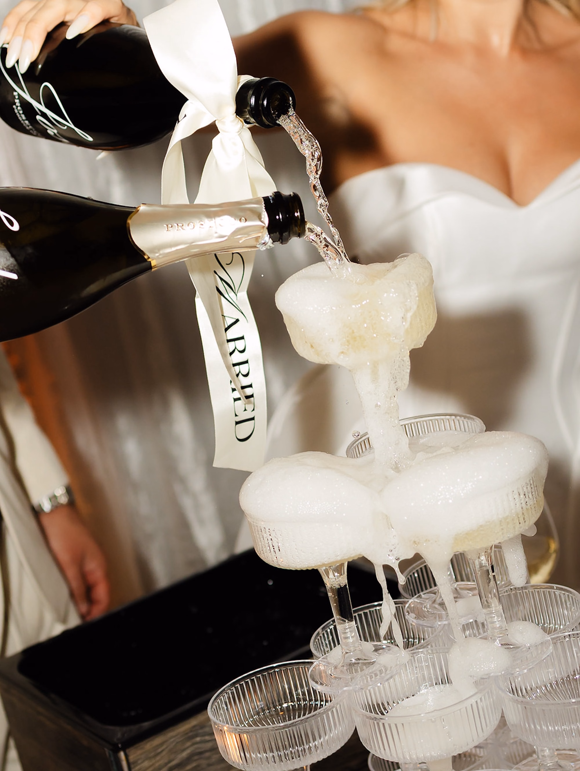 Bride Pouring Champagne into Coupe Glass Tower at Wedding Reception