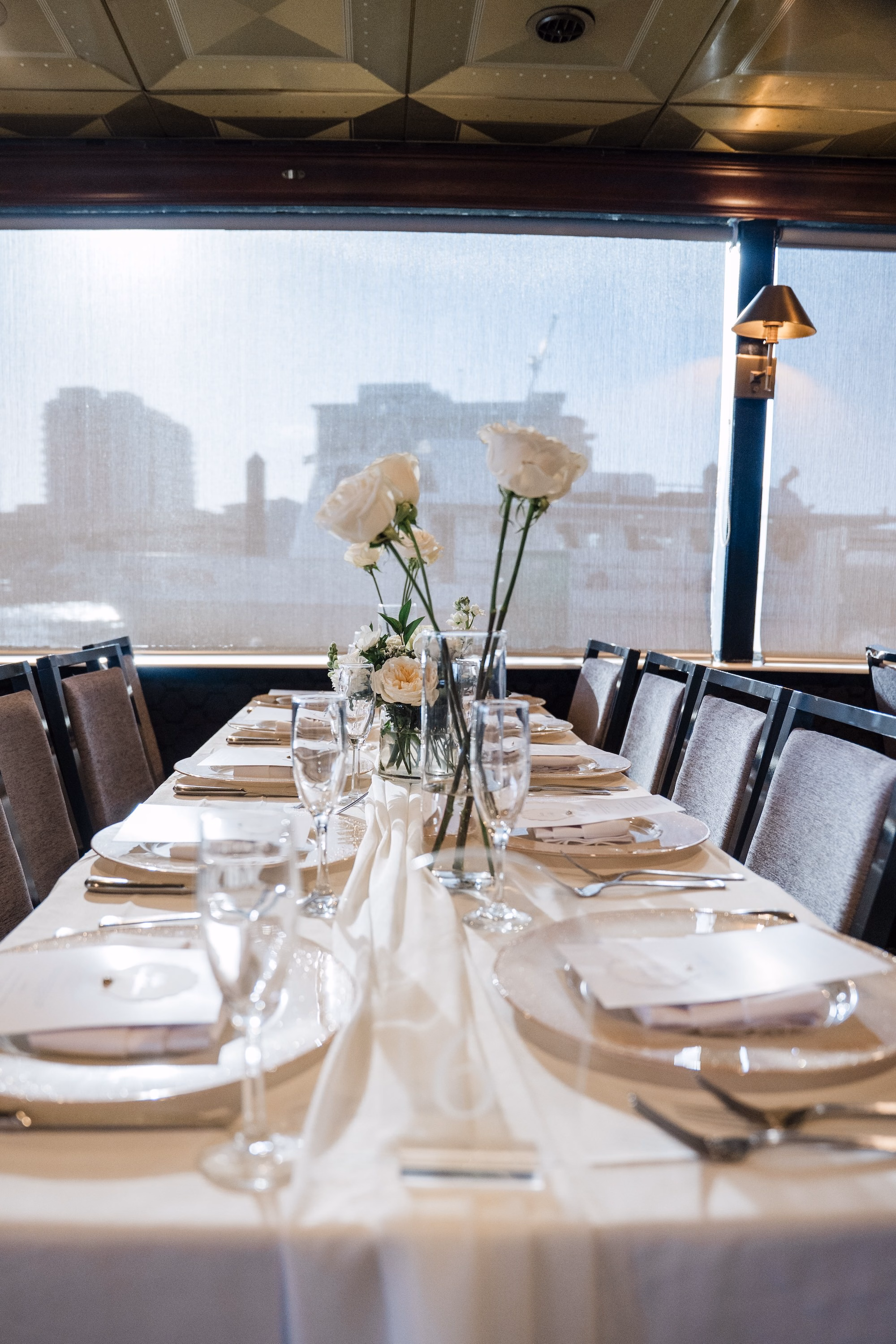 Long Wedding Reception Table with White Linens, Gold Chargers and White Rose Bud Vases Ideas | Spring Yacht Wedding Decor Inspiration | Clearwater Wedding Venue Yacht StarShip