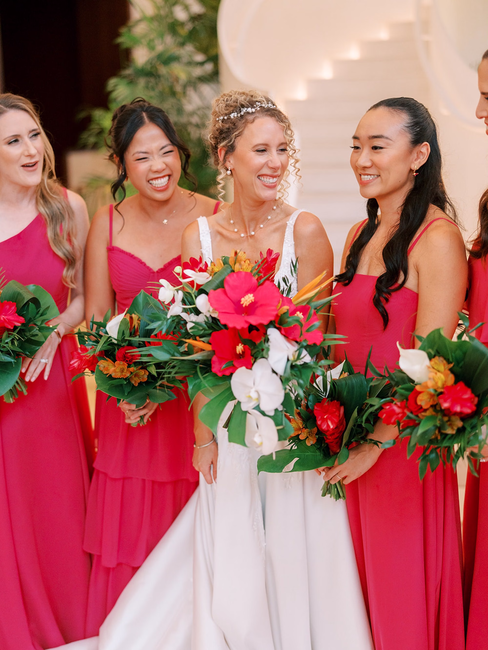 Bride Laughing with Bridesmaids in Hot Pink Dresses Holding Tropical Red Hibiscus and White Orchid Bouquets | Tampa Florist Monarch Events and Design | Hair and Makeup Adore Bridal