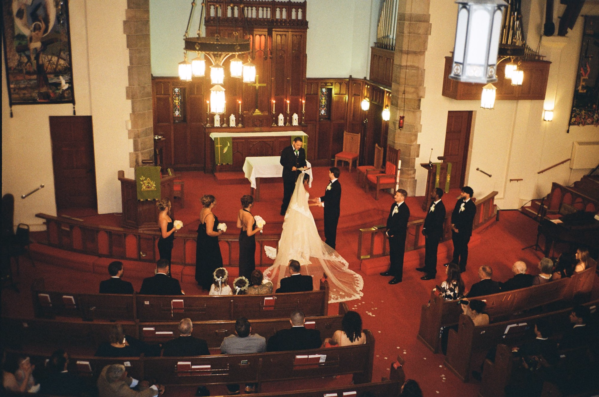 Aerial View of Church Wedding Ceremony with Red Carpet Aisle, Wooden Altar and Wedding Party in Black | Church Wedding Ceremony at St. Pete Venue Trinity Lutheran Church